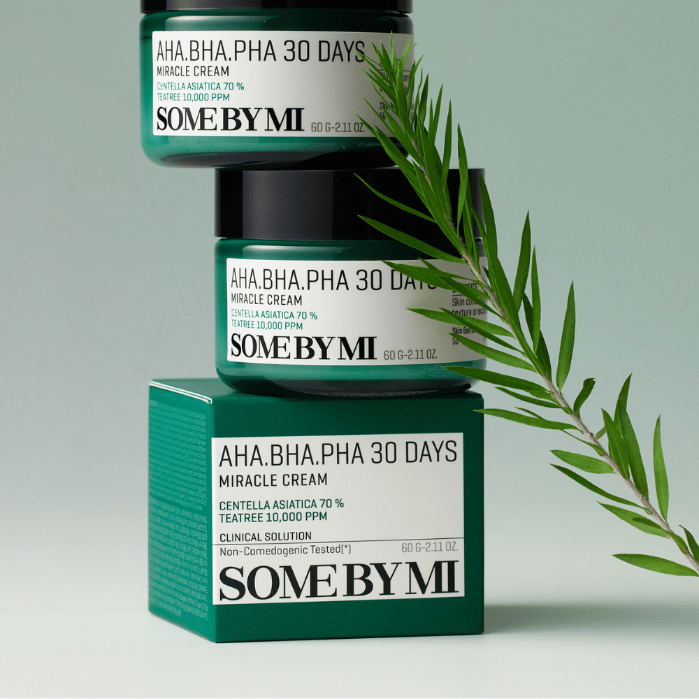 En bild som visar två burkar av "SOME BY MI AHA, BHA, PHA 30 Days Miracle Cream" staplade på en grönt tonad ruta. Krämen, som är rik på centella asiatica och tea tree-olja, är designad för att förbättra hudens kvalitet och lindra problemhud. Verkar återfuktande och lugnande.