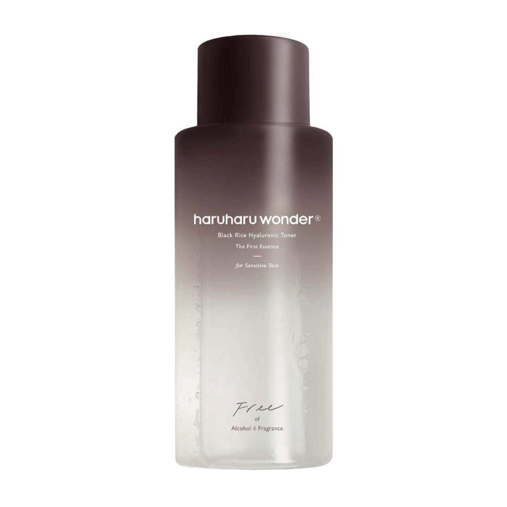 En flaska av haruharu wonder Black Rice Hyaluronic Toner The First Essence, med mörkbrun till genomskinlig gradient och texten "Free of Alcohol & Fragrance", på vit bakgrund.