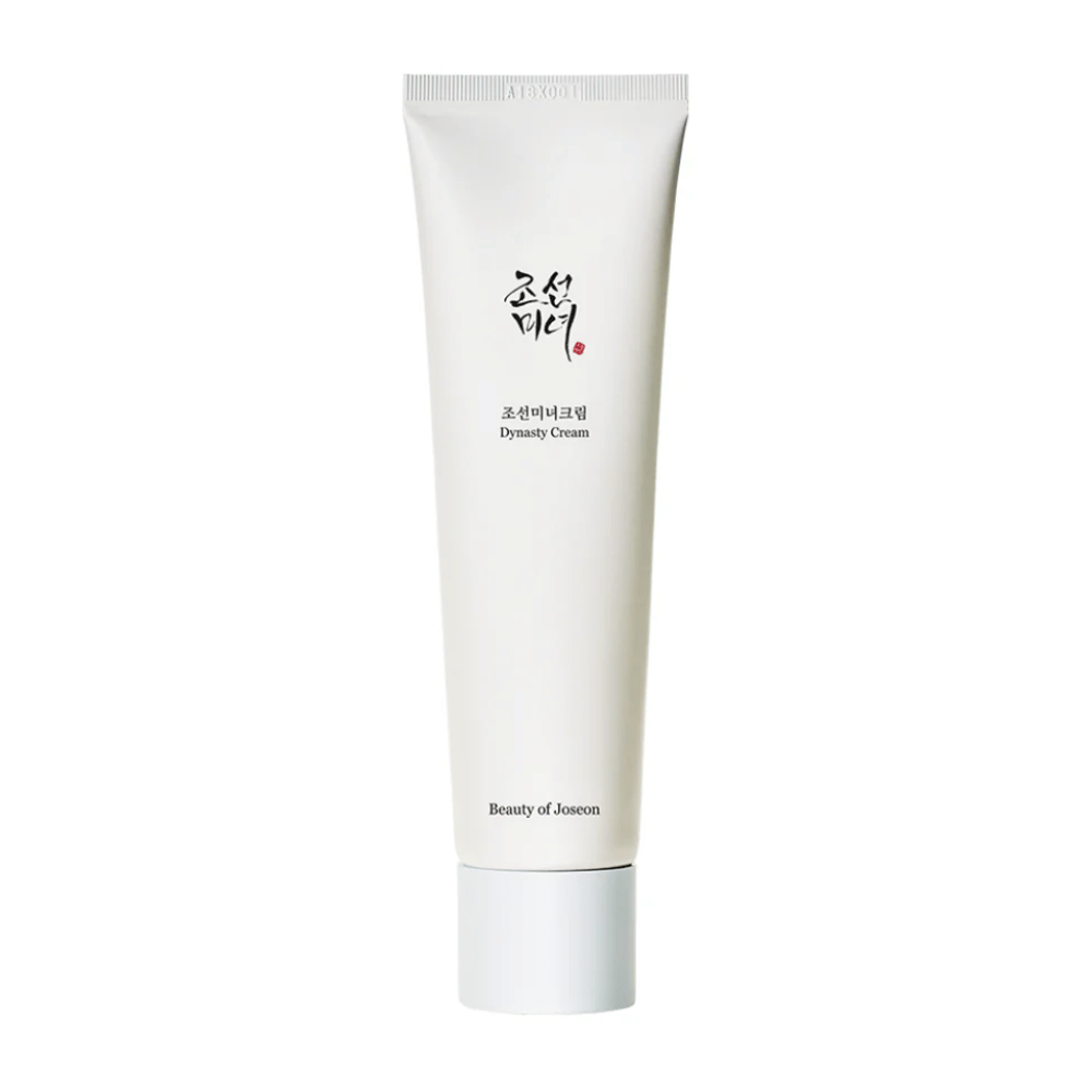 Bilden visar en tub av "Beauty of Joseon Dynasty Cream". Den slanka, vita tuben har minimalistiska designelement, inklusive elegant svart och röd text. Denna hudvårdsprodukt lovar att nära och vitalisera huden, vilket speglar de historiska skönhetssekretessen från Joseon-dynastin.