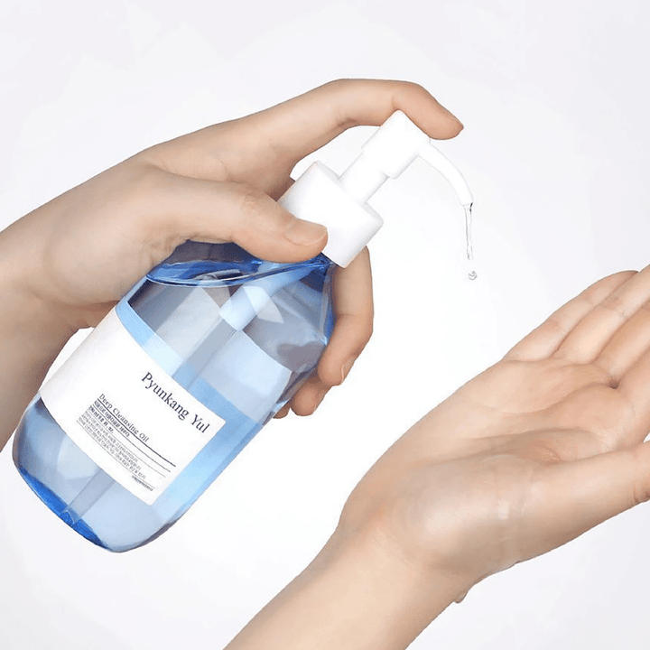 En kvinnas hand håller i en flaska Pyunkang Yul Deep Cleansing Oil 290ml.